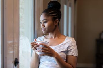 Woman holding a cup of tea and looking out of the window