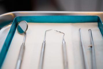 A set of dental tools are arranged on a tray.