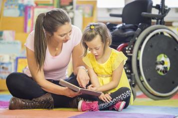 Woman with child with disability reading