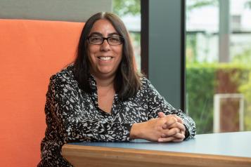 Chief Executive, Louise Ansari, sitting wearing black and white top and glasses.